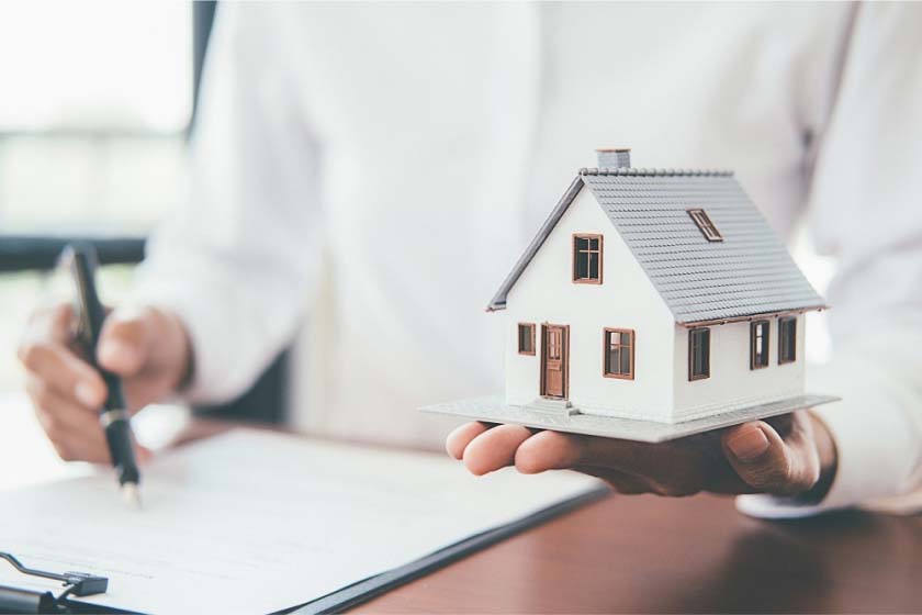 A miniature home model held in a woman's palm. 